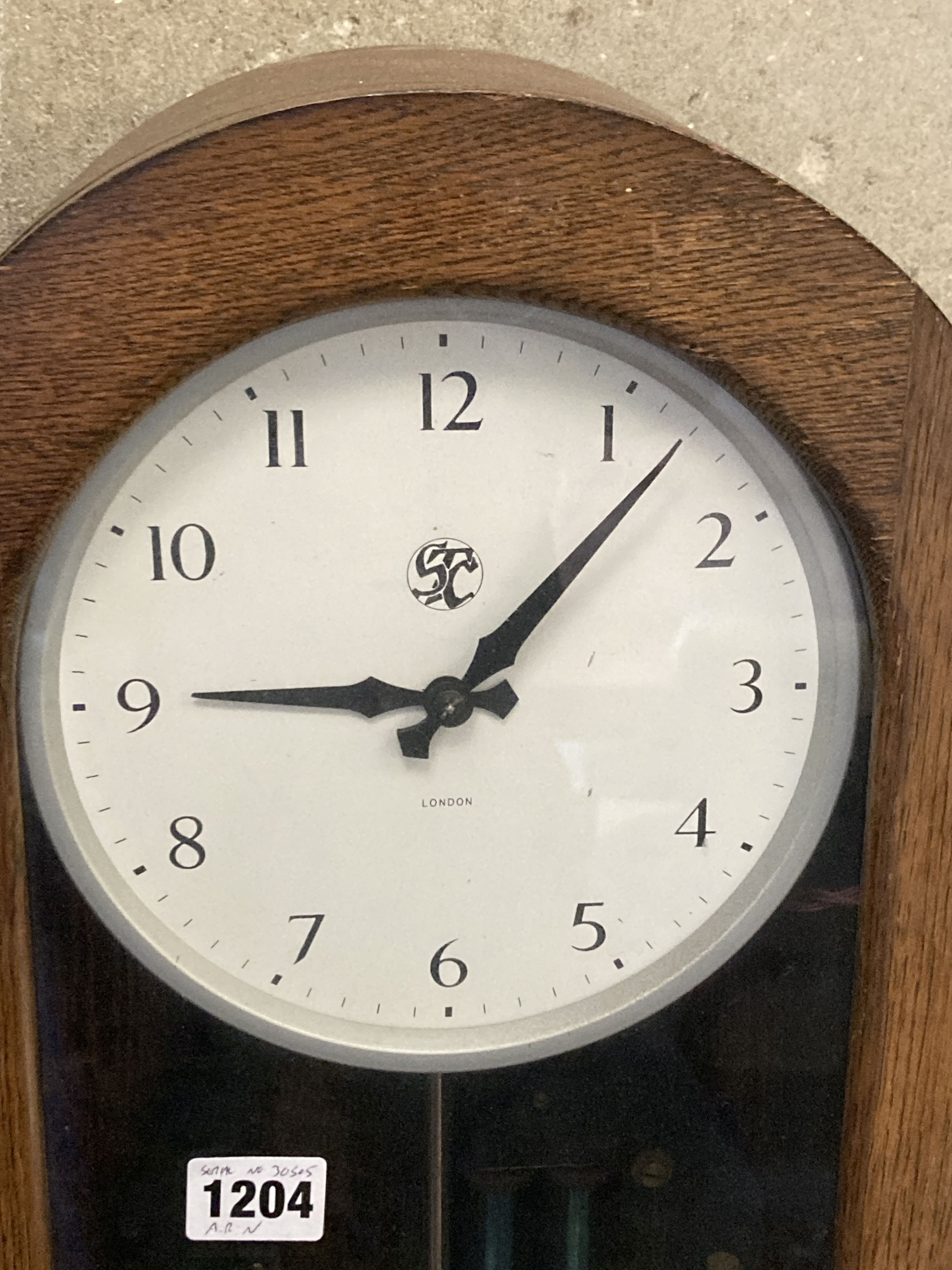 A Smiths English clock systems electric master clock in an arched oak case, with associated pendulum bob, marked ARN Serial No. 30505,